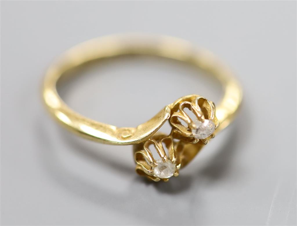 A George V 18ct gold and two stone diamond set crossover ring, size O/P, gross 2.7 grams.